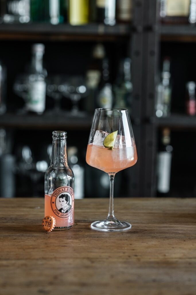 Lillet Jolie Drinkbild im Weinglas mit Limettenschnitz und Thomas Henry Pink Grapefruit